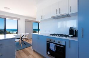 扬巴Edgewater 1 - LJHooker Yamba的一间设有蓝色橱柜的厨房和一间享有海景的用餐室