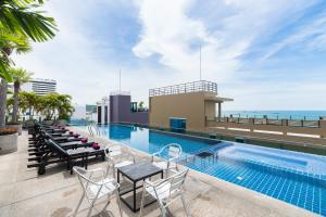 芭堤雅市中心春之海酒店的一座带桌椅的游泳池位于酒店大楼旁