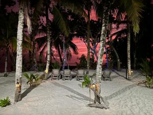 Anse Kerlan开普吉恩玛丽海滩别墅的海滩上,有椅子和棕榈树,日落