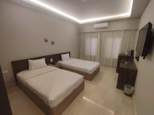 赫尔格达Al Dora Residence Suites Hurghada的酒店客房设有两张床和电视。