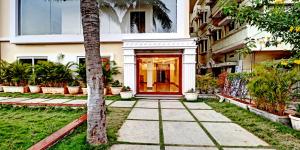 卡基纳达De Crown Luxury Hotel的一座有红色门和棕榈树的建筑