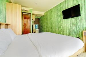 万隆OYO Life 93065 Apartemen Gateway Pasteur By Glory Rent的卧室配有白色的床和平面电视。