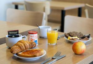 拉内斯泰尔B&B HOTEL Lorient Lanester的一张桌子,上面放着两盘早餐食品和苹果