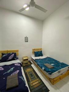 亚娄Razumi's Homestay的一间卧室配有两张床和吊扇