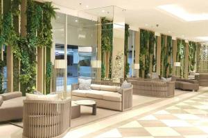 泗水Tanglin Orchard Apartment (2BR)的大堂的墙壁上摆放着长沙发和植物