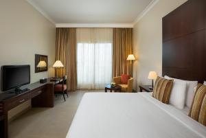 阿布扎比Metropolitan Al Mafraq Hotel的酒店客房设有一张大床和一台电视。