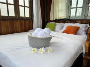 Chiang KlangDee Tor Jai Farm Stay ดีต่อใจฟาร์มสเตย์的床上一篮毛巾和鲜花
