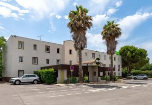 圣让德韦达B&B HOTEL Montpellier 1的停车场前方的棕榈树建筑
