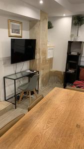 巴黎阿特利尔蒙特吉尔19号公寓的客厅配有桌子、书桌和电视。