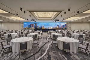 新加坡Hilton Singapore Orchard的宴会厅配有白色的桌椅和大屏幕
