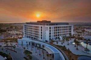 阿布扎比Doubletree By Hilton Abu Dhabi Yas Island Residences的背景日落的酒店 ⁇ 染