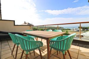 圣梅尔林Beachside apartment, sea views的阳台上的木桌和椅子