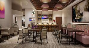 迈尔斯堡The Banyan Hotel Fort Myers, Tapestry Collection by Hilton的一间带桌椅的餐厅和一间酒吧