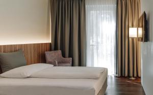 施韦夏特HEINhotel vienna airport的卧室配有床、椅子和窗户。