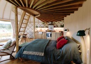 GodshillTree Field Yurt at Moor Farm的一间卧室配有一张带红色枕头的大床