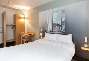 圣博内德米尔B&B HOTEL Lyon Saint-Bonnet Mi-Plaine的酒店客房设有一张大床和一张书桌。