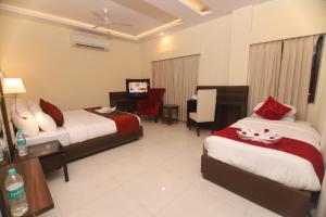 瑞诗凯诗Hotel Indira Nikunj的酒店客房配有两张床和一张书桌