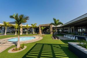 巴利托864 Ballito Hillis Luxury Estate Family Apartment的一座带游泳池、棕榈树和大楼的度假村