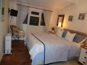 埃文河畔斯特拉特福Log Cabin, Conveniently Situated halfway between Stratford and Warwick的一间卧室配有一张床和一把椅子,还有两个窗户