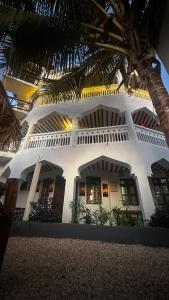 南威Light of Zanzibar Hotel的一座白色的建筑,前面有棕榈树