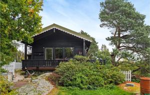 法尔松3 Bedroom Cozy Home In Farsund的院子里有栅栏的黑色小房子