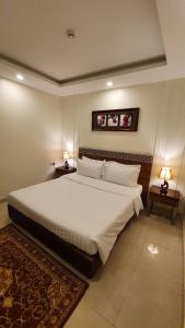 延布منتجع شاطئ الدولفين للإيواء السياحي的一间卧室配有一张带两盏灯的大型白色床。