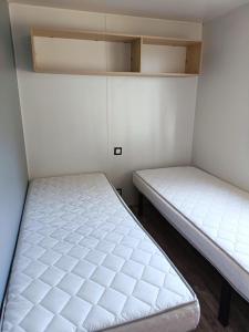 基伯龙Mobilhomes Quiberon Camping Conguel - Bord de Mer的配有白色墙壁的小客房内的两张床