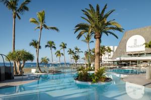 卡门港Plus Fariones Suite Hotel的一座棕榈树和海洋游泳池