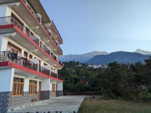 达兰萨拉Happy home stay, Dharamshala的一座建筑,设有红色的阳台,背景是群山