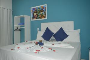马拉戈日Pousada Vovó Zilda Maragogi的卧室配有白色的床铺,上面有红色的鲜花