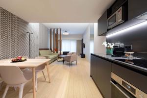卢森堡The Central Kirchberg - Smart ApartHotel的厨房、带桌子的客厅和用餐室