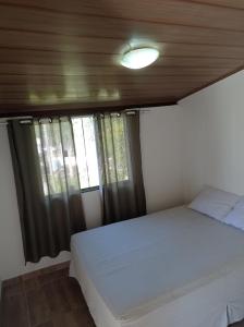 瓜拉派瑞sítio recanto verde do sol的卧室配有白色的床和窗户。