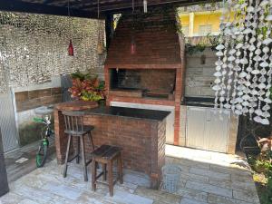 卡博迪圣阿戈斯蒂尼奥Casa Praia de Gaibu的室外厨房配有砖炉和凳子