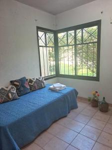 卢汉德库约Rincón Verde Chacras de Coria的一间卧室配有一张带蓝色床单的床和两个窗户。