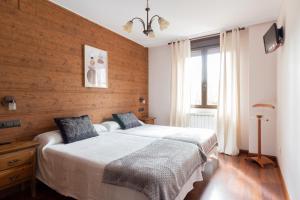 Cubillas de Arbas里奥假日乡村酒店的一间卧室设有一张床和木墙