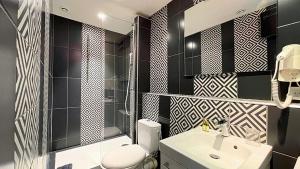 戛纳乐弗洛里安酒店的浴室设有黑色和白色的瓷砖墙壁和水槽