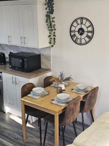戴斯Serviced Apartment - Aberdeen的餐桌、椅子和墙上的时钟