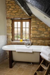 奇平卡姆登The Ebrington Arms的带浴缸的石质浴室设有窗户。