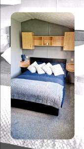 OrbyHerons Mead Touring Park and Fishing Lakes - Plot 18的一间卧室配有蓝色的床和白色枕头