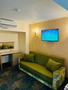BabadauHotel La Ane的客厅配有绿色沙发和墙上的电视