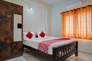 班加罗尔Oyo Flagship Sri Chowdeshwari Boarding And Lodging的一间卧室配有一张带红色枕头的床和一扇窗户