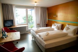 斯图加特阿巴理想酒店的酒店客房设有两张床、一张桌子和一台电视。