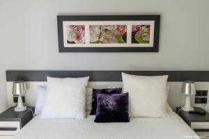 里瓦德塞利亚Apartamento - Riba De Sella的卧室配有白色床和紫色枕头