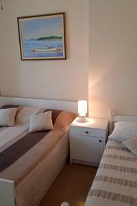 扎格拉维奇Apartments by the sea Cove Ostricka luka, Rogoznica - 11451的一间卧室配有两张床和一张带台灯的桌子