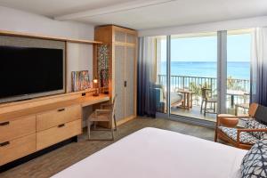 卡胡库海龟湾度假酒店的一间卧室配有一张床、一台电视和一个阳台