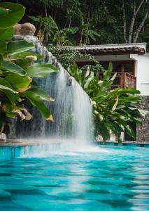 圣赫罗尼莫Bio Rio Hotel的瀑布,在泳池上方,有蓝色的海水