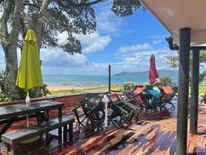 库珀海滩Driftwood Lodge Beachfront, Cable Bay, Coopers Beach, Northland的一个带桌椅的甲板和一把遮阳伞