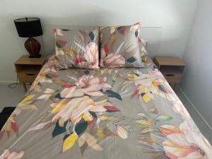 彩虹海滩Rainbow Shores Resort, Baden North的一张带花卉棉被和2晚床头柜的床