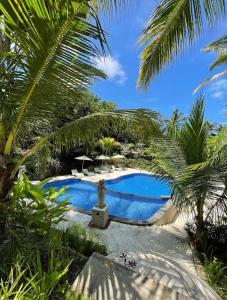 珀尼达岛Bila Penida Resort & Farm的棕榈树旁的一座带雕像的游泳池