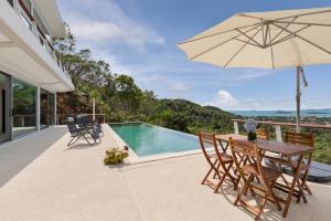 苏梅岛TWO SISTERS HILL Villa - Spectaculaire vue sur mer的一个带桌子和遮阳伞的庭院和一个游泳池